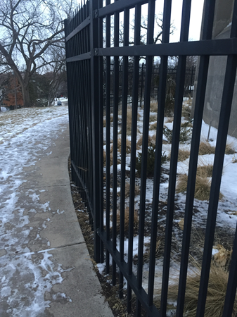 A fence curving around a walkway littered with snow